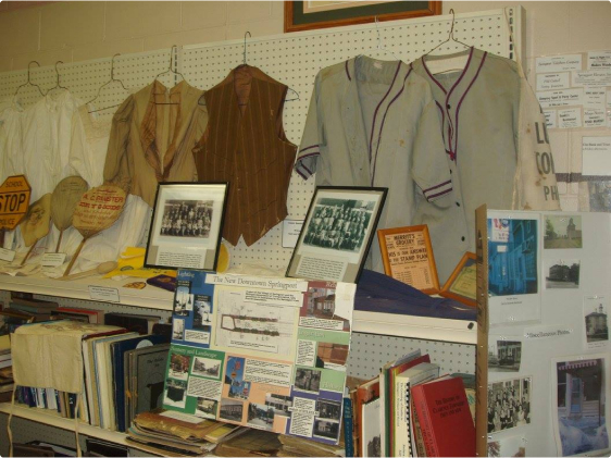 Assorted antique vests and cardigans and various old photographs.