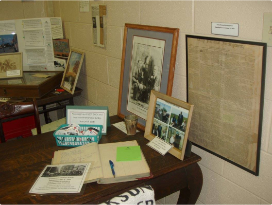 The History Room guest book, along with several old photographs and a framed copy of an old newspaper.
